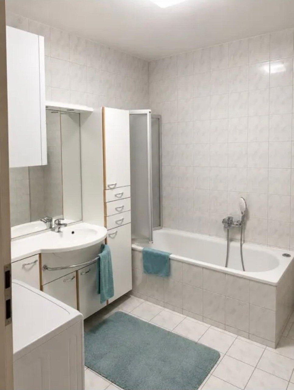 Badezimmer mit Badewanne, Waschtisch und Waschmaschine